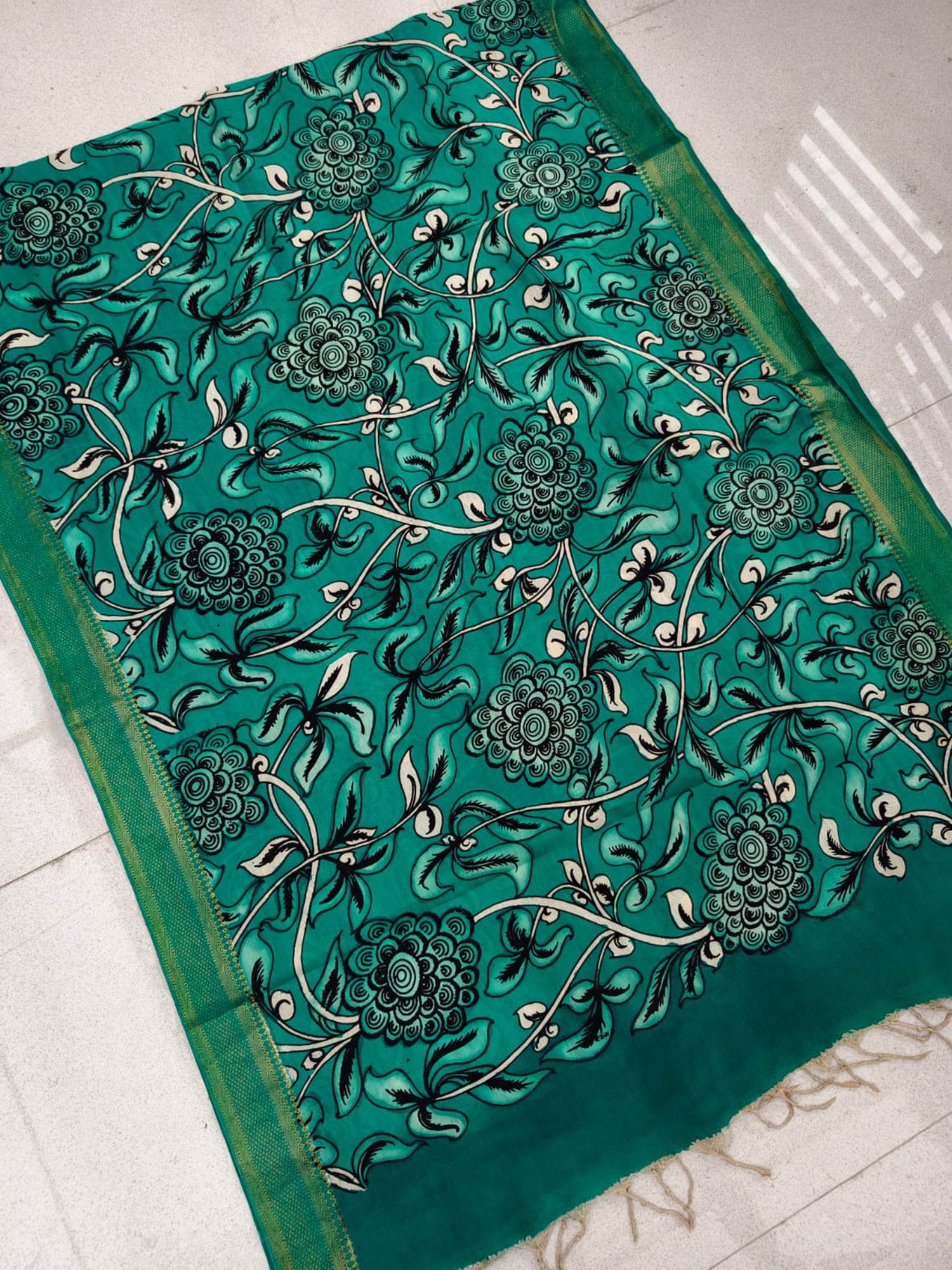 A green hand-painted Kalamkari dupatta with floral patterns from Mrida.