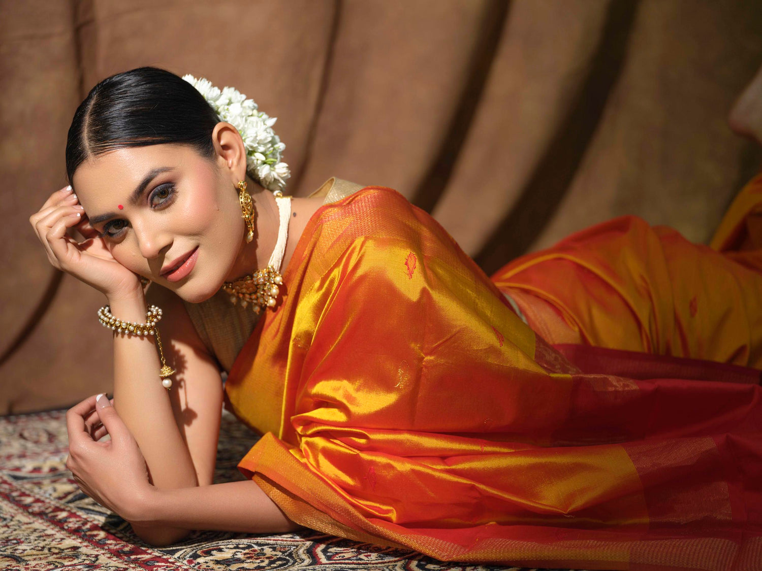 A close up shot of a women in a Pure and Certified Handloom Mustard & Red Maheshwari Mulberry Silk Saree, from the festive collection by Mrida